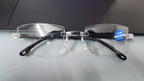 Rimless reading glasses with +3.00 power sticker on the lens